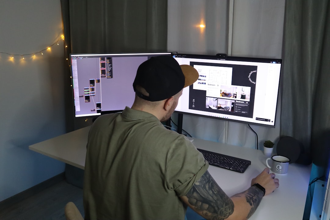 man in green dress shirt and black cap sitting in front of computer — IL WebDesign Manhattan