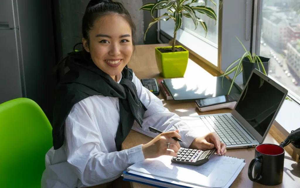 Smiling accountant at a desk with a laptop and calculator