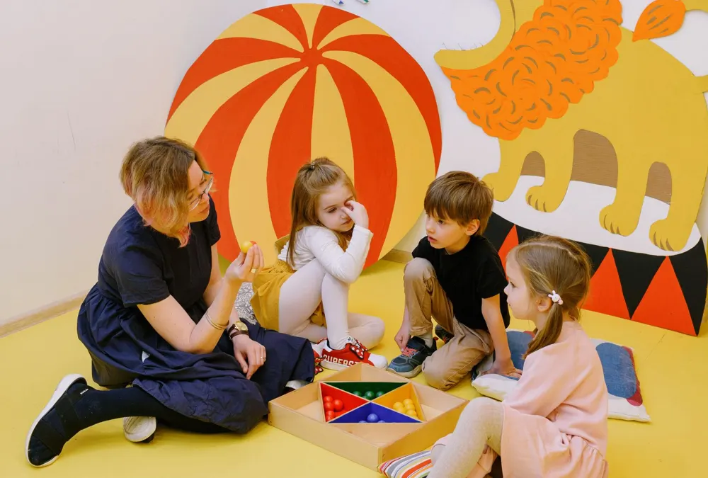 Preschool teacher and children playing together in a colorful classroom