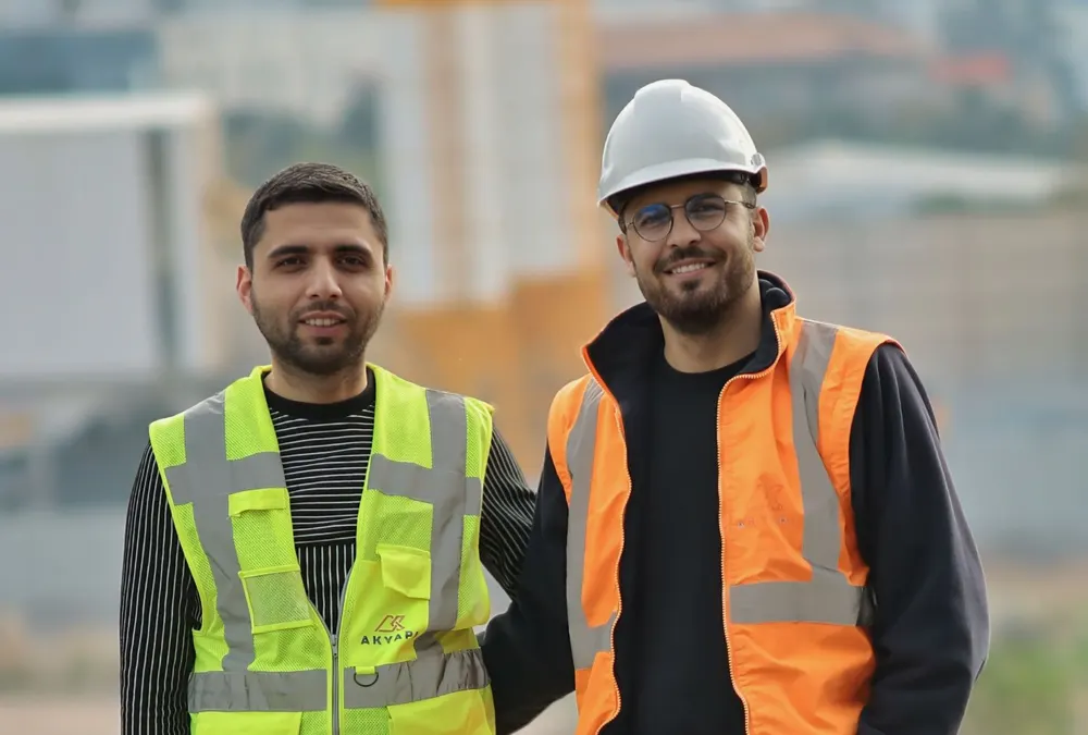 Two construction team members in safety vests standing on a job site
