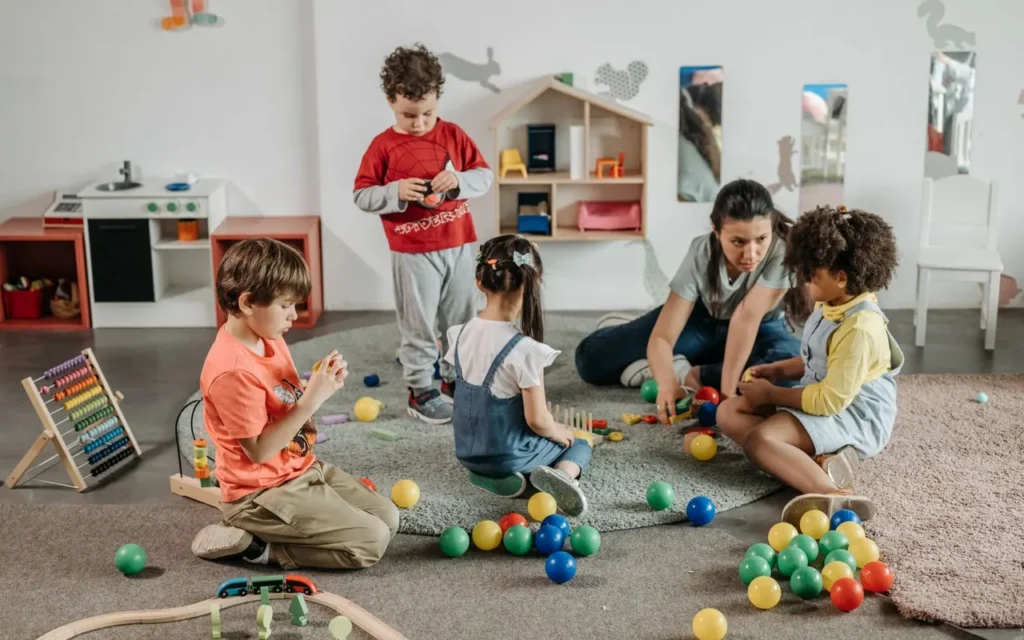 Teacher playing on the floor with preschool children and toys