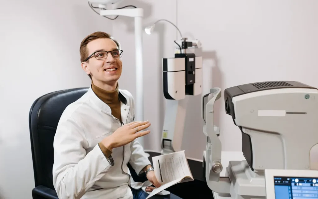 Smiling optometrist in an exam room with eye testing equipment