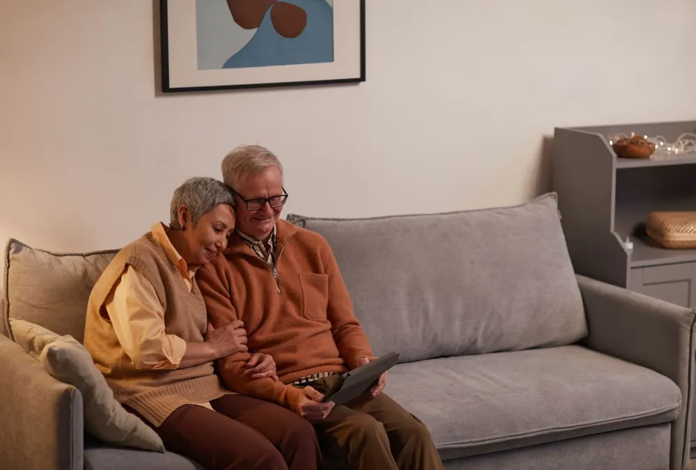 Senior couple sitting together on a sofa with a tablet