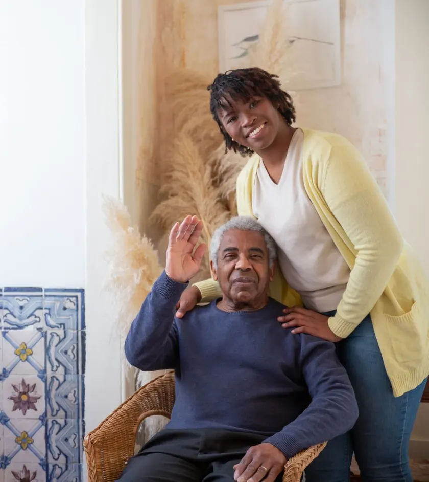 Smiling caregiver standing beside a senior man at home