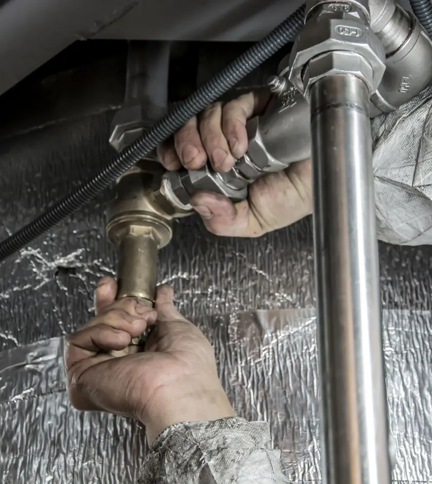 Technician tightening brass pipe fittings on a plumbing and heating system