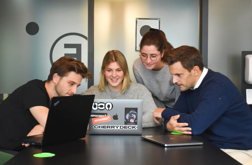 Web development team collaborating around a laptop while planning a custom business website
