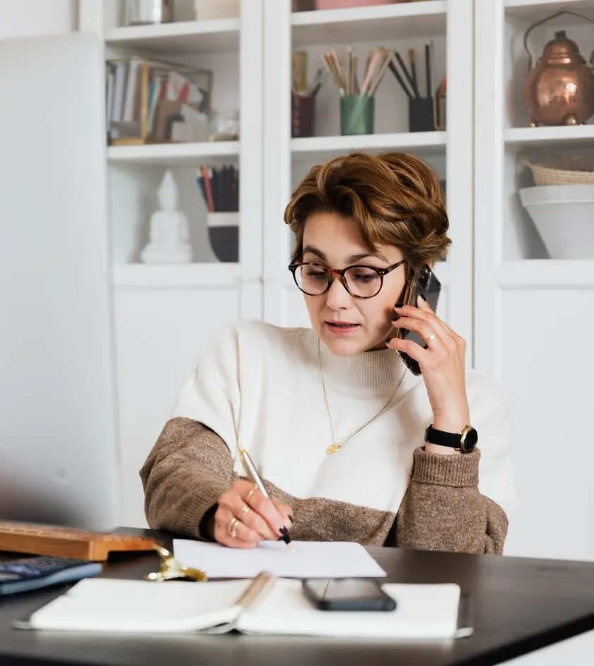Professional taking notes while on a client intake phone call