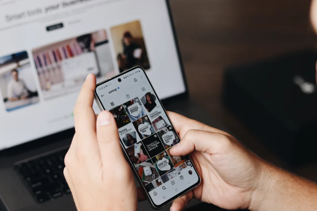 Person browsing a mobile-responsive landing page on a smartphone in front of a laptop