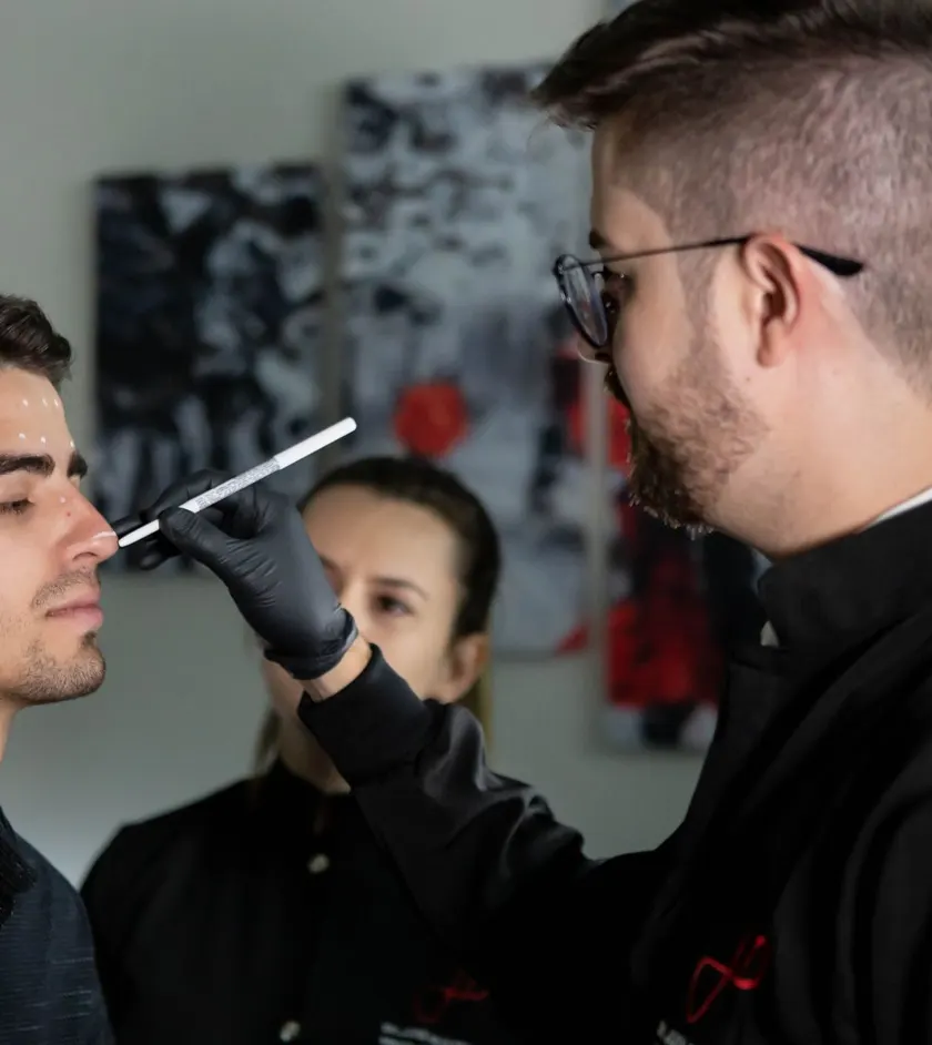 Surgeon assessing a patient’s nose during a consultation