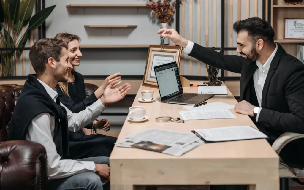 Real estate agent handing house keys to a couple at a desk