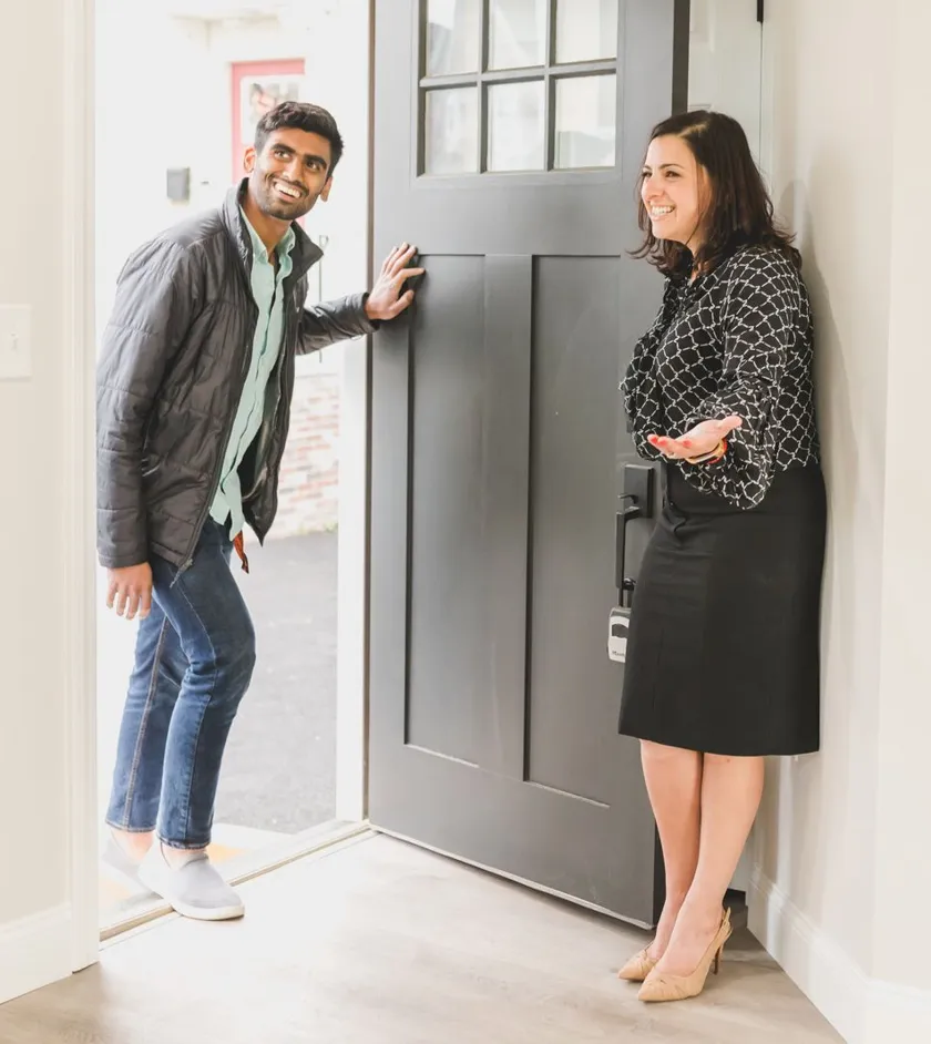 Real estate agent welcoming a client at the front door of a home