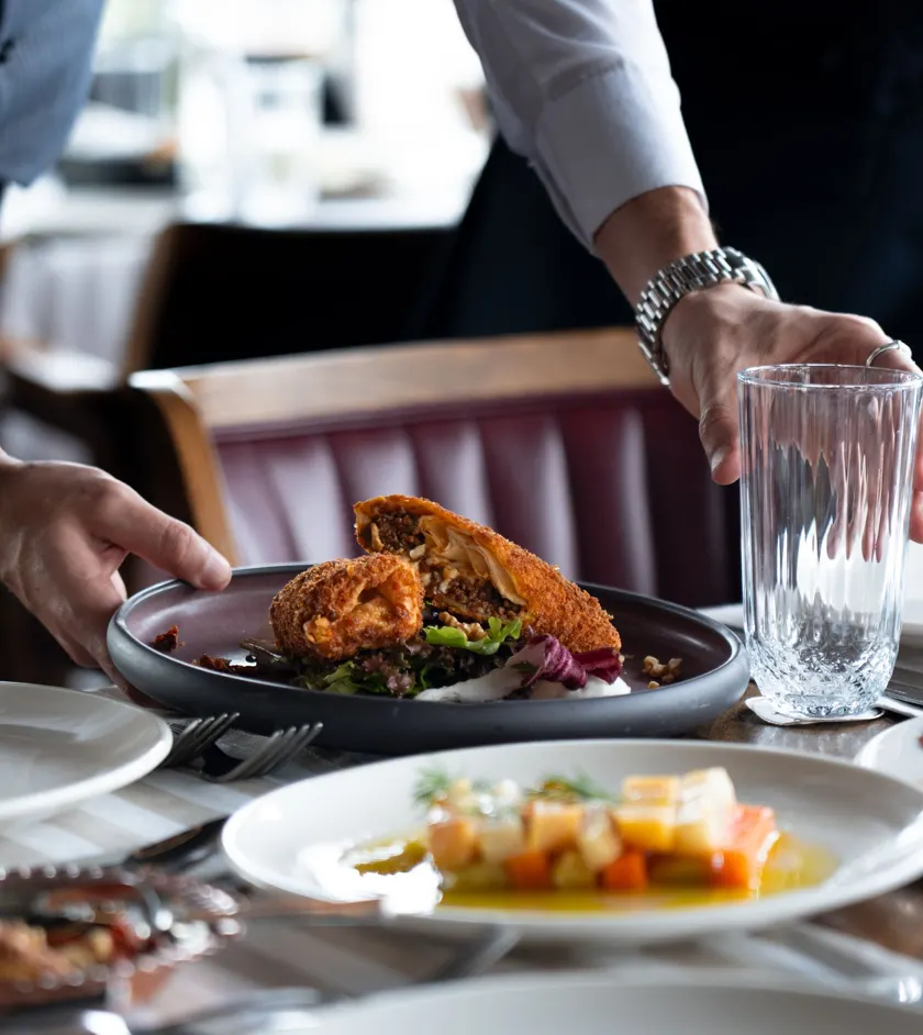 Server placing a plated entrée on a restaurant table