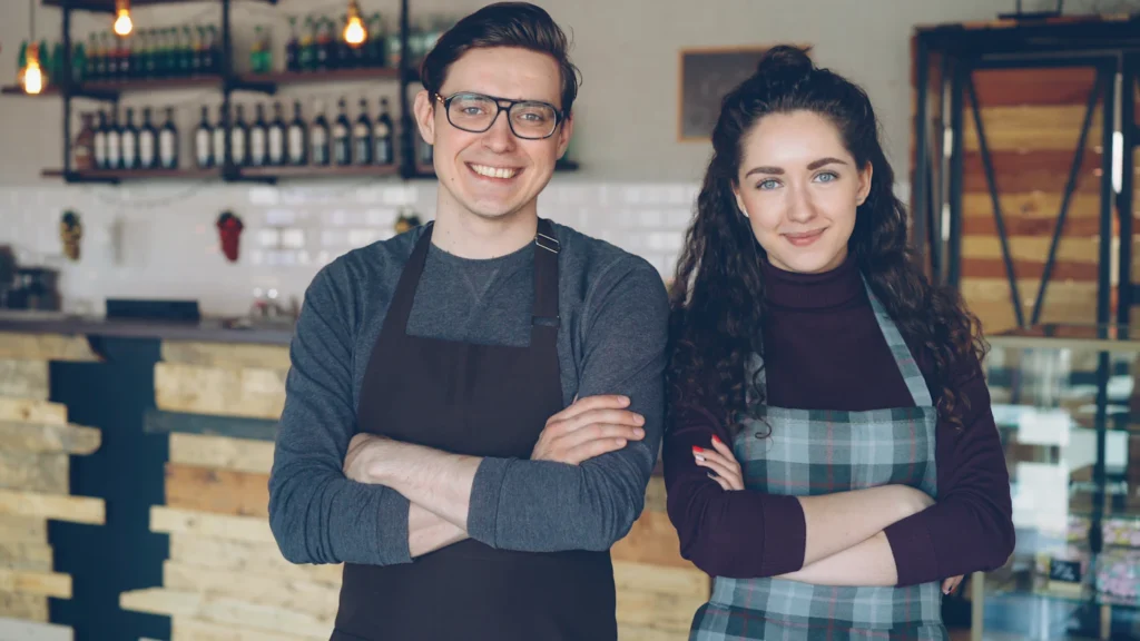Smiling small business owners standing in their cafe after growing customers with local SEO