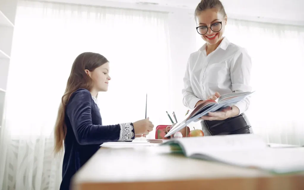 Teacher guiding a girl through a lesson in a bright classroom