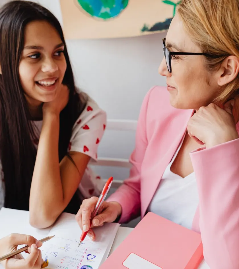 Student and teacher smiling over a worksheet